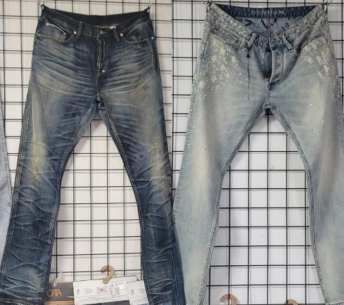 Two pairs of washed denim jeans with different fades and treatments on a grid display.