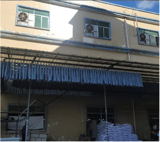 Garments hanging to dry outside an industrial building.