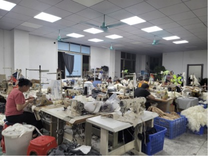 A designer working at a large table in a bright fashion studio with male and female dress forms.