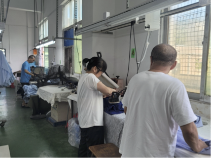 Busy garment workshop with patterned fabrics, technical folders, and clothing racks in the background.