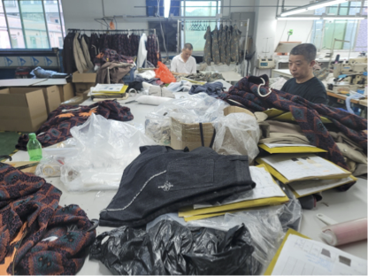 Workers at ironing and heat-pressing stations finishing garments in an industrial workshop.