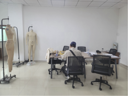 Rows of industrial sewing machines with workers at stations in a bright manufacturing floor.