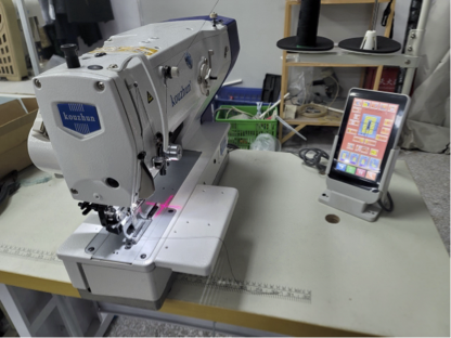 Industrial computerized sewing machine with laser guide and touchscreen control panel.